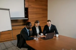 HOA management professionals reviewing a website on a laptop while discussing common website mistakes and strategies to improve performance and user experience.
